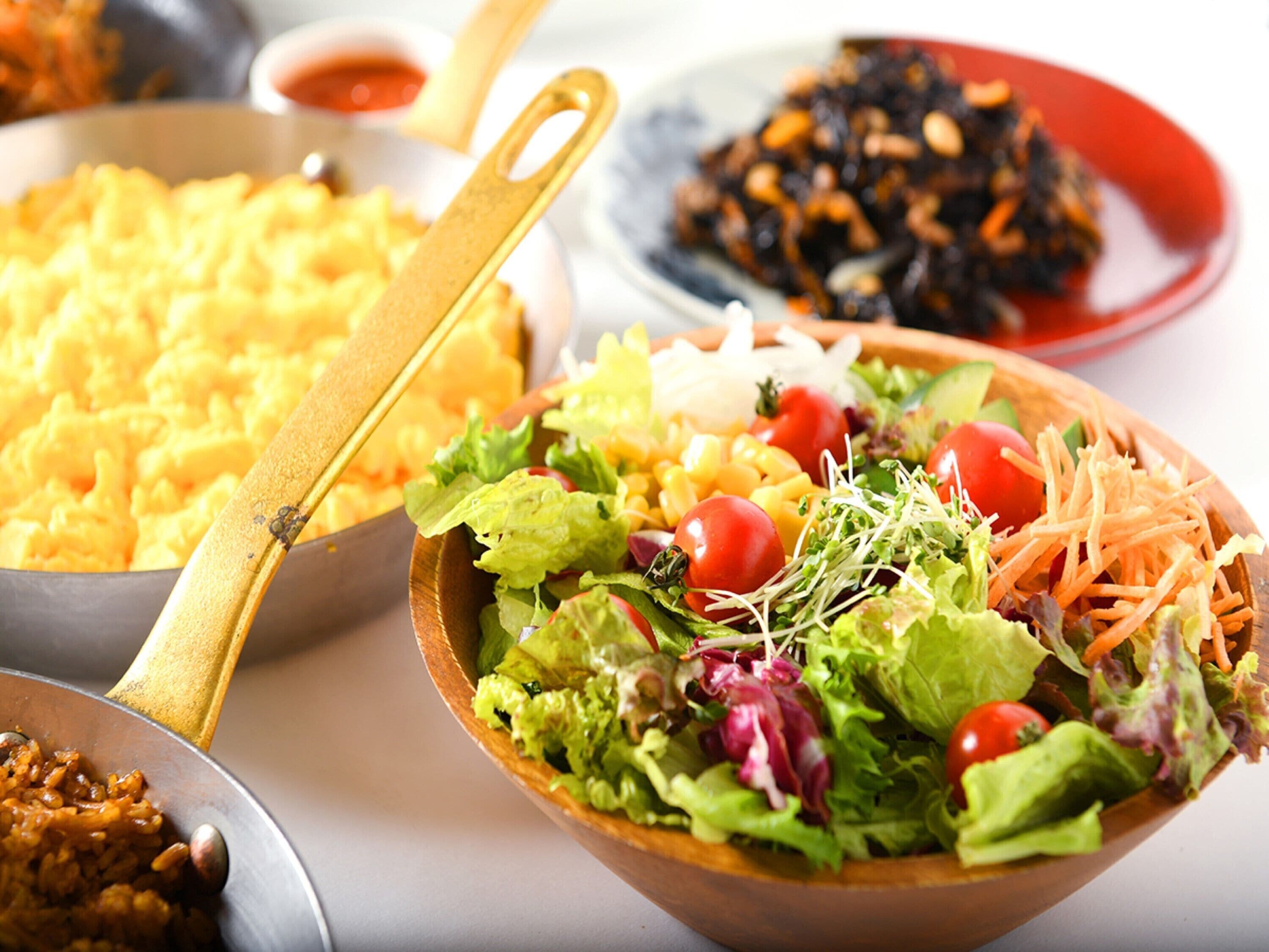 A variety of dishes including a salad, rice, and a bowl of what appears to be a bean dish.