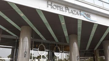 The entrance of Hotel Plaza Kobe with a modern design, featuring large glass windows and a prominent sign.