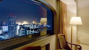 Habitación de hotel con un amplio ventanal que ofrece vistas nocturnas de la ciudad.
