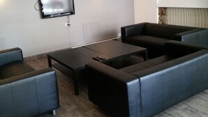 A modern living room with a sofa set, a coffee table, and a flat-screen TV mounted on the wall. - Roligheden Ferieleiligheter (Kristiansand)