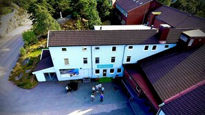 An aerial view of a building with multiple floors, a parking area, and a group of people gathered in front. - Roligheden Ferieleiligheter (Kristiansand)