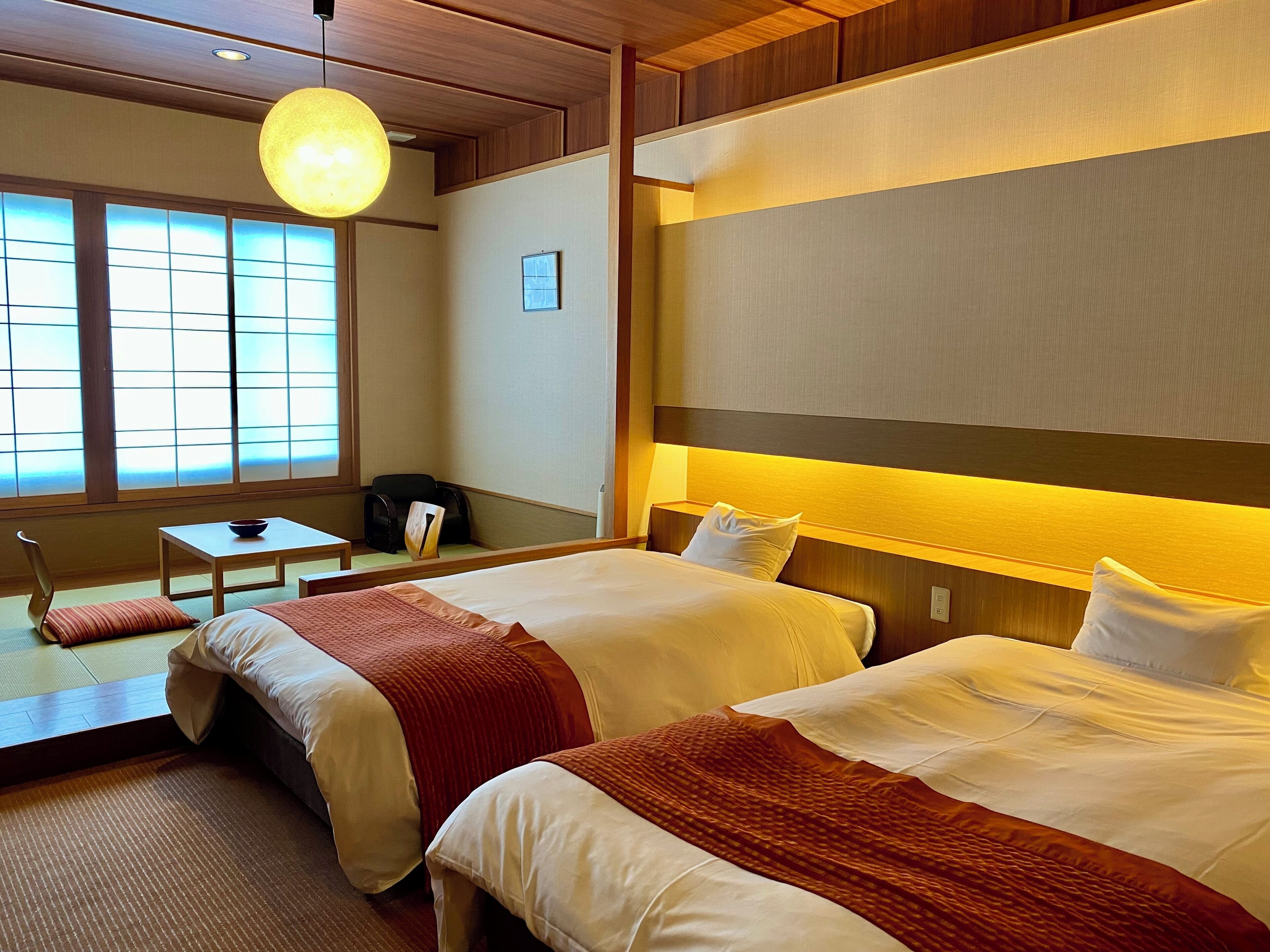 A hotel room with two beds, a desk, and a chair.