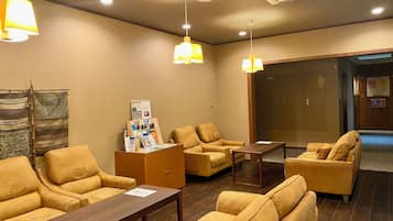 A waiting area with leather sofas, a wooden table, and a bulletin board with information.
