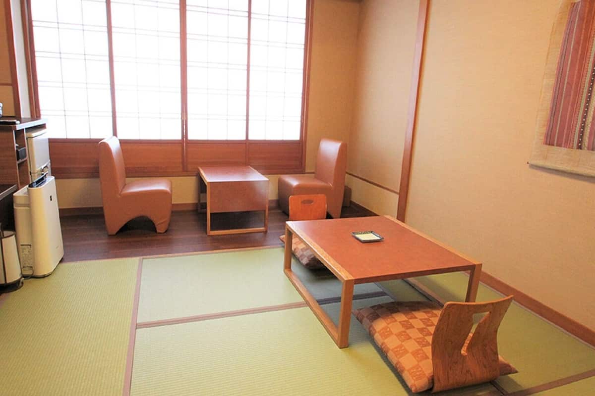 Una habitación japonesa tradicional con suelo de tatami, una mesa baja, un sofá y un televisor.