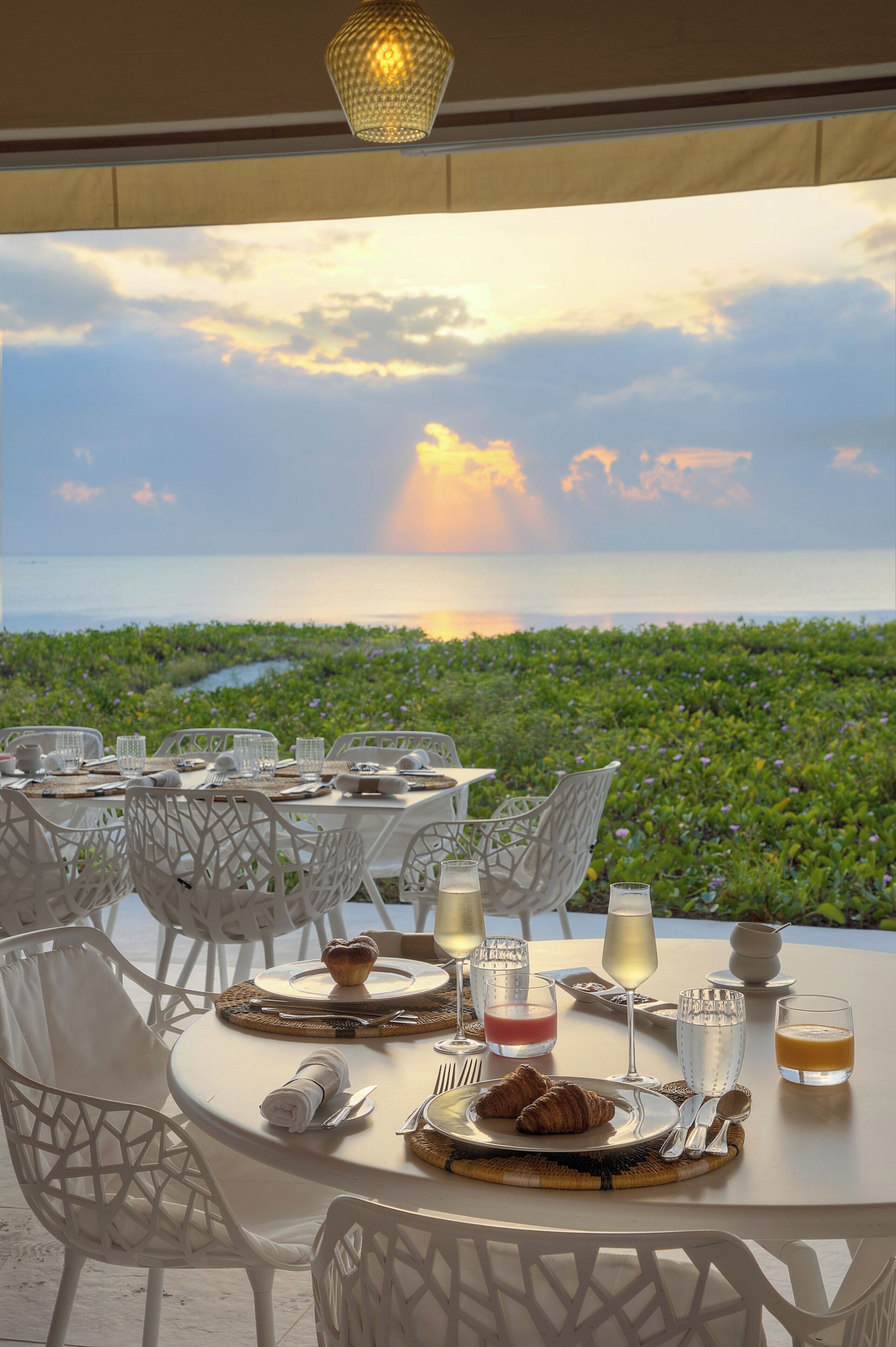 Une table dressée pour le petit-déjeuner, avec vue sur l’océan et la verdure.