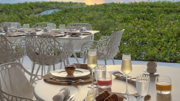 A table set for breakfast with a view of the ocean and greenery.