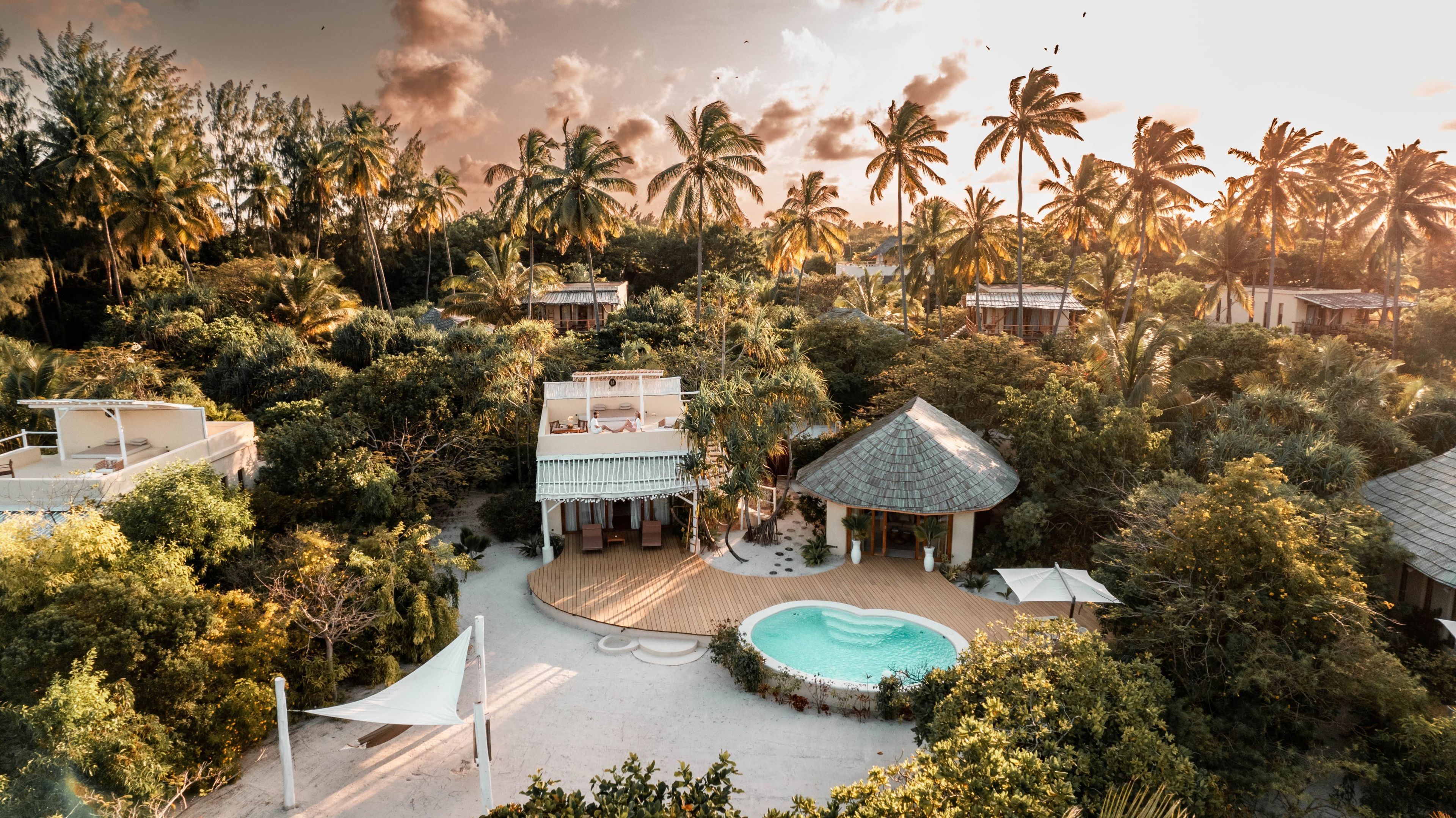 Un resort con piscina, varias edificaciones y abundante vegetación tropical.