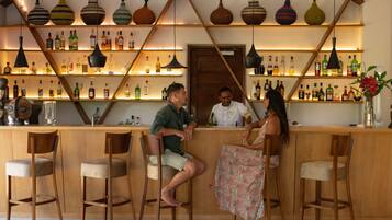 Una zona de bar con sillas de madera, una barra y estantes llenos de botellas.