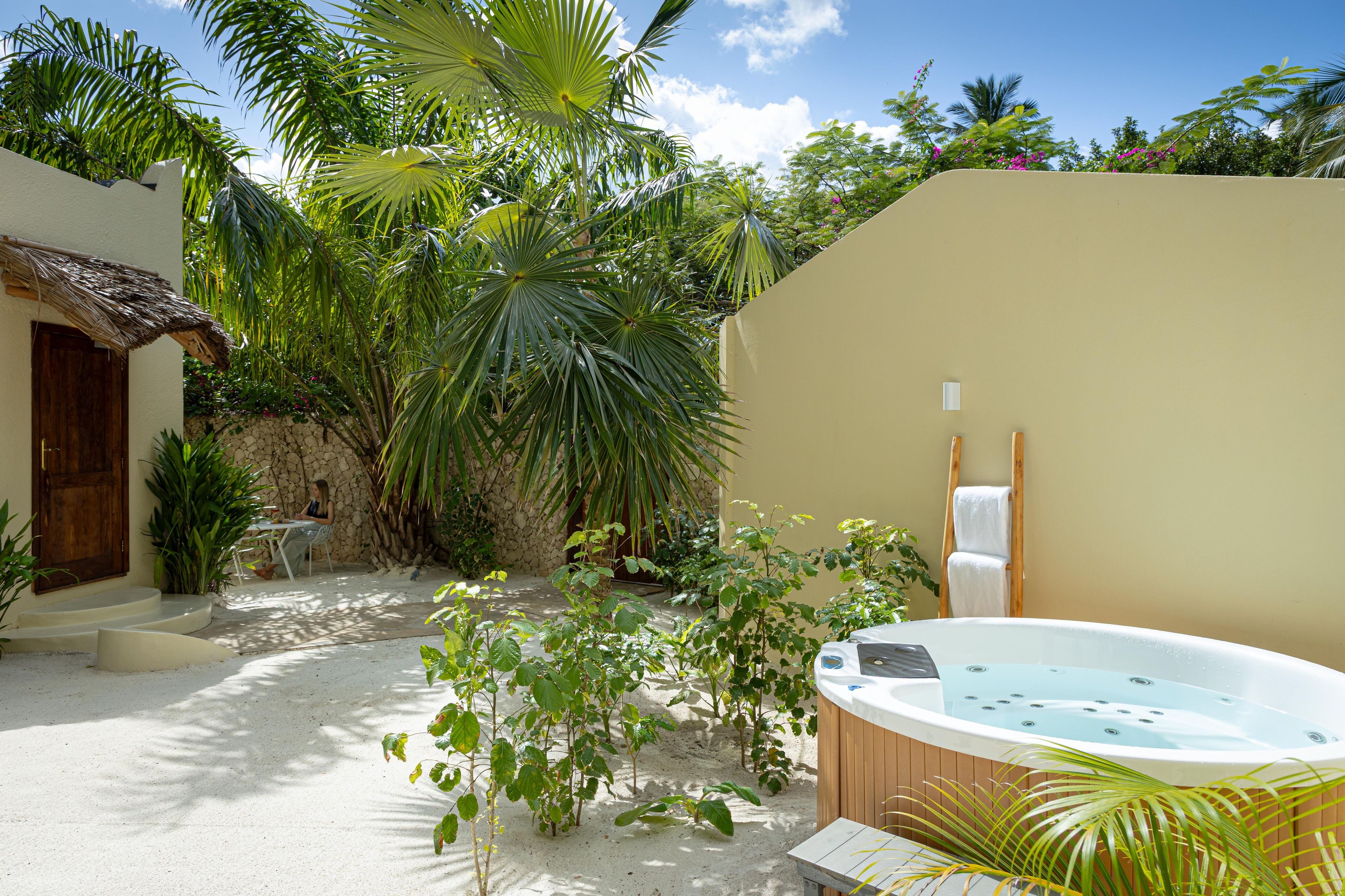 A spa area with a hot tub, a wooden ladder, and a stone wall.