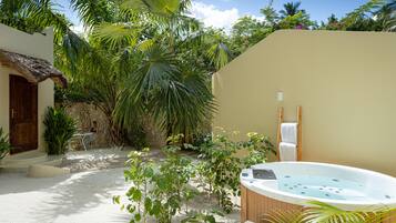 A spa area with a hot tub, a wooden ladder, and a stone wall.