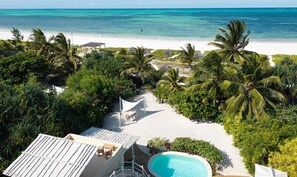 Een resort met een zwembad, strand en palmbomen.