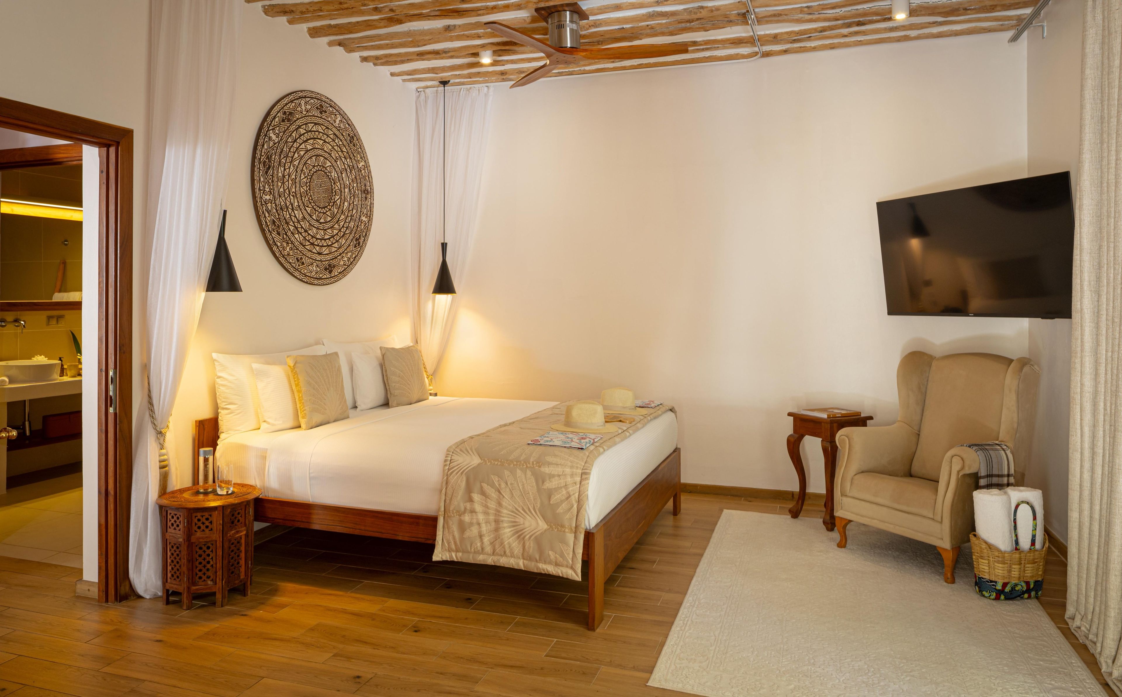 Ein Hotelzimmer mit Bett, Nachttisch, Stuhl, Fernseher und einem großen Wandbild.