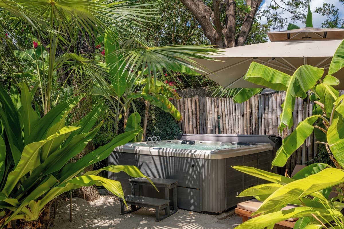 A hot tub surrounded by lush greenery and a bamboo fence.