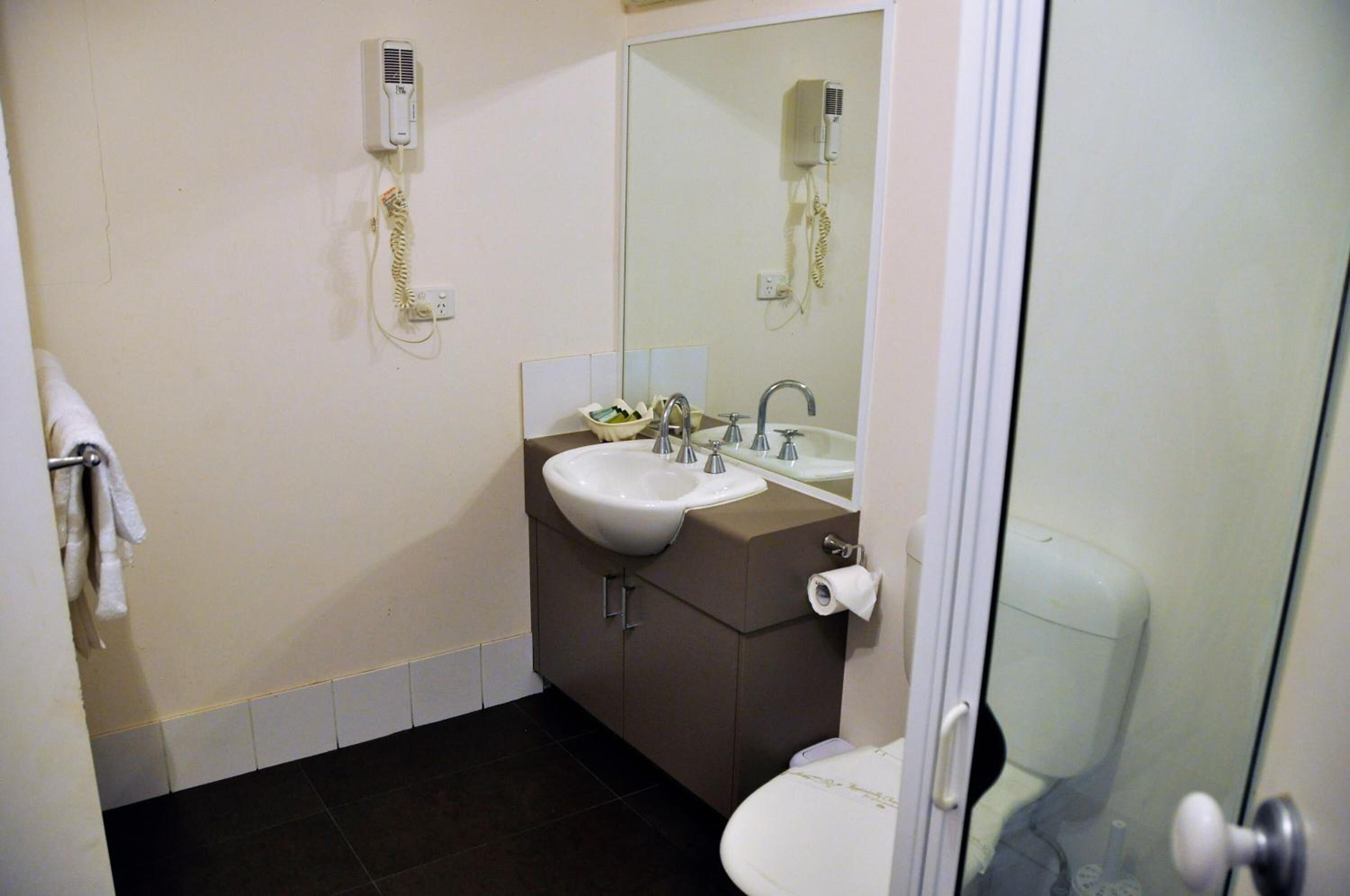 Un baño con lavamanos, espejo e inodoro.