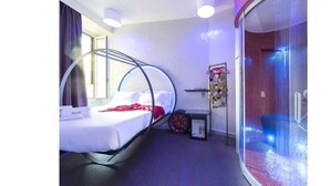 Una habitación de hotel moderna con una cama, un ventanal circular y una zona de ducha.