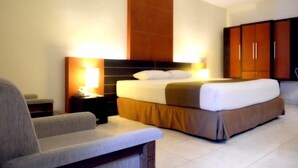 Una habitación de hotel con cama, mesita de noche, lámpara y armario.