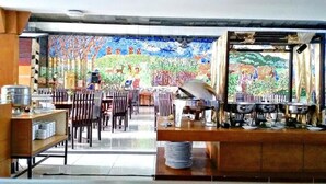 Un restaurante con un mural en la pared, sillas de madera y una barra con equipo de cocina.