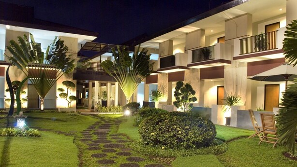 Un patio de hotel moderno con un césped cuidado, un camino de piedra y diversas plantas.