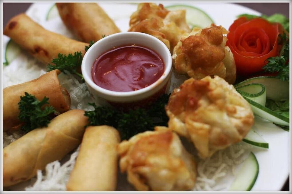 A plate of spring rolls and a small bowl of dipping sauce.