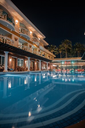 Een hotel met een zwembad, terras en overdekt gedeelte.