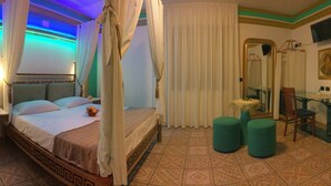 A four-poster bed with a canopy, a bedside table, a mirror, a green ottoman, and a patterned floor. - Villa Masseria Marini (San Giuseppe Vesuviano)