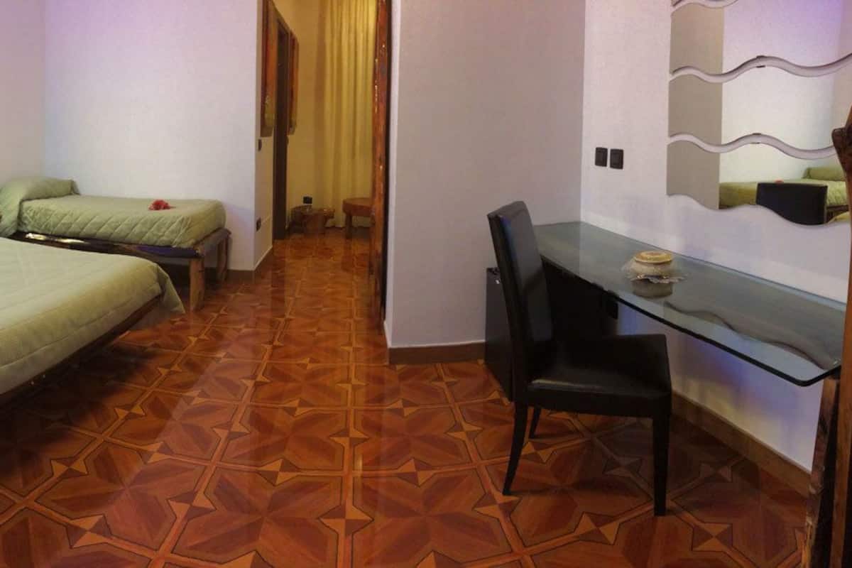 Une chambre d’hôtel avec deux lits, un bureau et une chaise.
