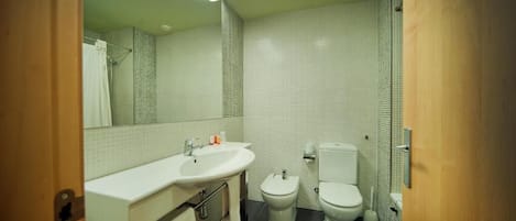 A bathroom with a white sink, two toilets, and a mirror.