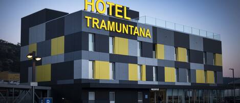 A modern hotel building with a checkered facade and a prominent 'HOTEL TRAMUNTANA' sign.