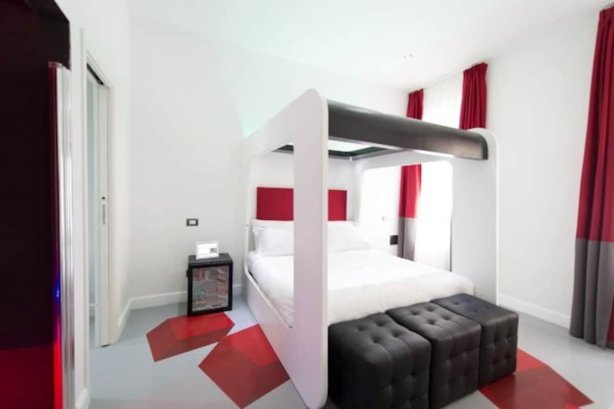 Una camera da letto moderna con un letto a castello, un comodino, una lampada e una combinazione di colori rosso e bianco.