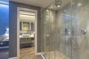 A modern bathroom with a glass-enclosed shower, a vanity with a sink, and a mirror.