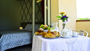 Ett välordnat frukostbord med croissanter, en fruktskål, en kanna och en vas med blommor.