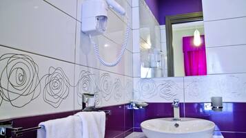 A modern bathroom with a white sink, purple walls, and a mirror with a purple curtain.