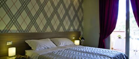 A hotel room with a bed, nightstands, a lamp, and a view of the outside.