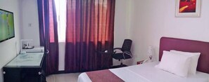 Una habitación de hotel con cama, escritorio, silla y televisor.