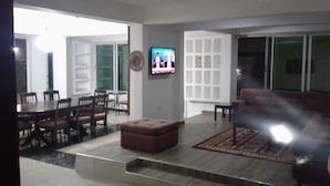 A living room with a TV, a dining area with chairs and a table, and a sofa. - Lane Residence (Accra)