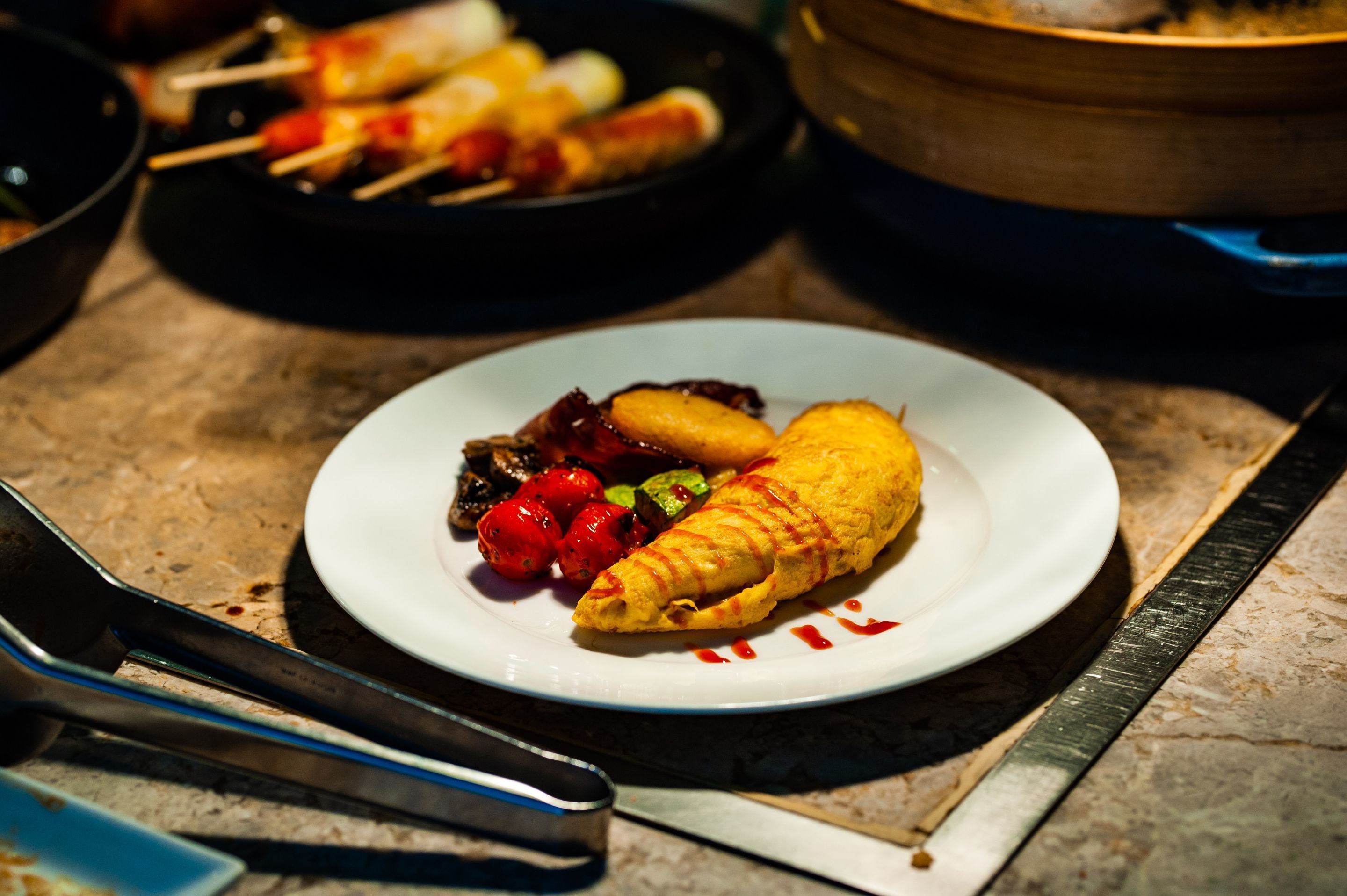 A plate with a rolled omelette, cherry tomatoes, and grilled vegetables.