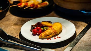 A plate with a rolled omelette, cherry tomatoes, and grilled vegetables.