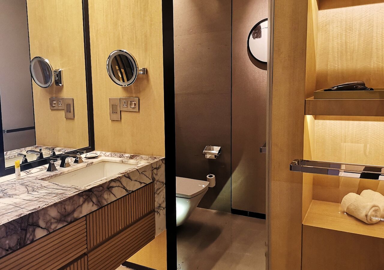 A modern bathroom with a marble sink, a toilet, and a towel rack.