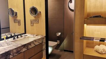 A modern bathroom with a marble sink, a toilet, and a towel rack.