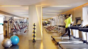 Une salle de sport équipée de tapis de course, de ballons d’exercice et d’appareils de musculation.