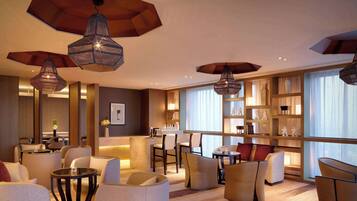 A modern hotel lobby with seating areas, a reception desk, and a bar.