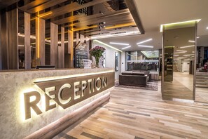 Ein Empfangsbereich mit einem Holzbüro, einem Empfangsschild und einer Treppe zu anderen Teilen des Gebäudes.