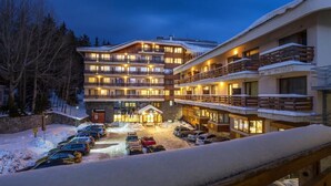 Ett hotell med flera våningar, balkonger, en parkeringsplats och snö på marken.