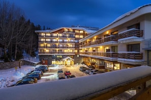 Ein mehrstöckiges Hotel mit Balkonen, einem Parkplatz und Schnee auf dem Boden.