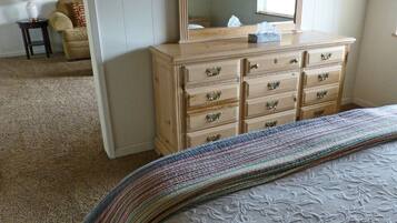 A bedroom with a bed, a dresser, a mirror, and a chair.