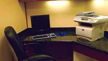 A small office space with a desk, a printer, a computer monitor, and a chair.