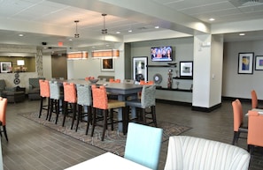 A hotel lobby with a large bar area, seating, and a television screen.