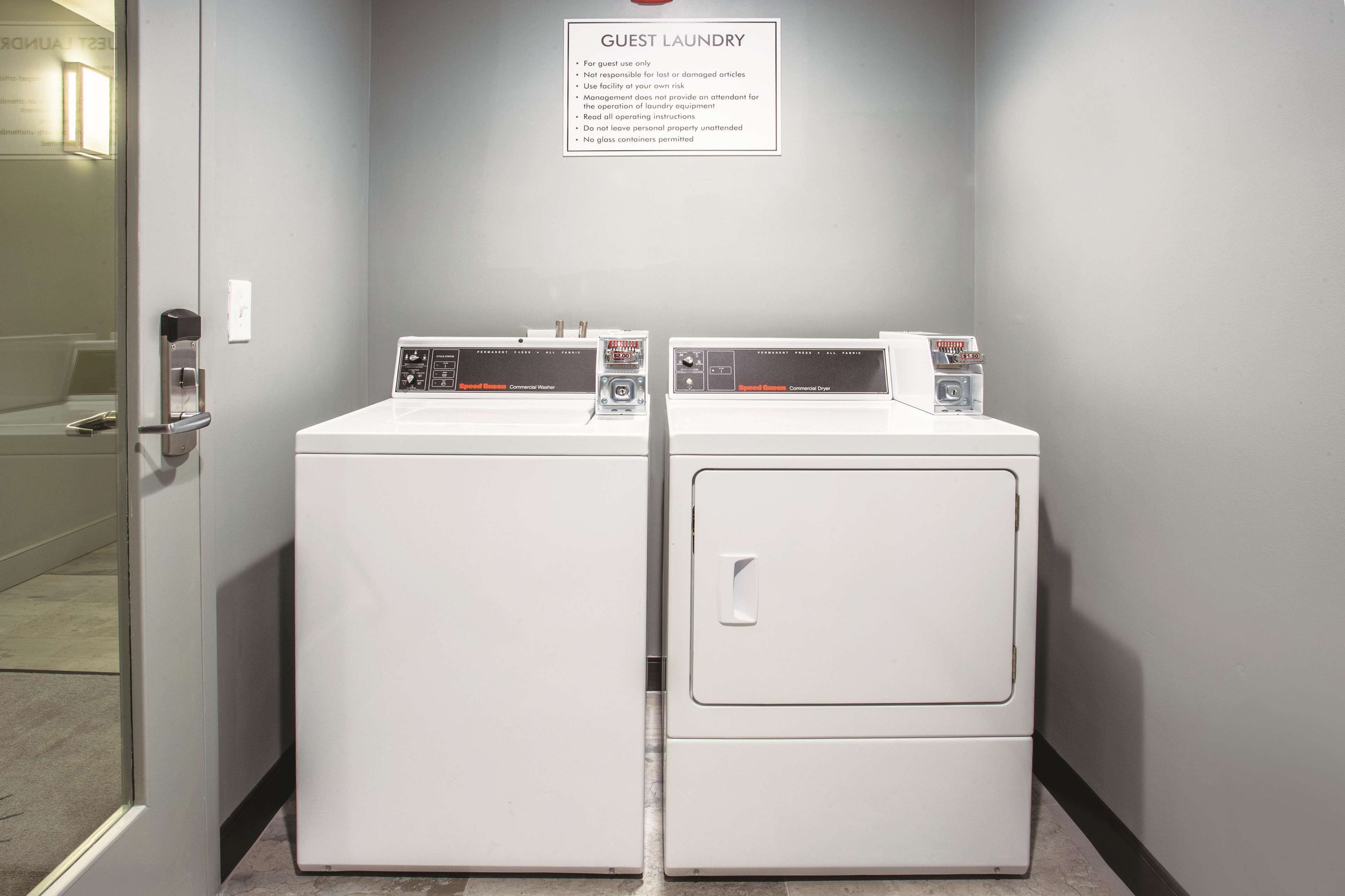 A guest laundry area with two stacked washing machines and a sign with laundry instructions.