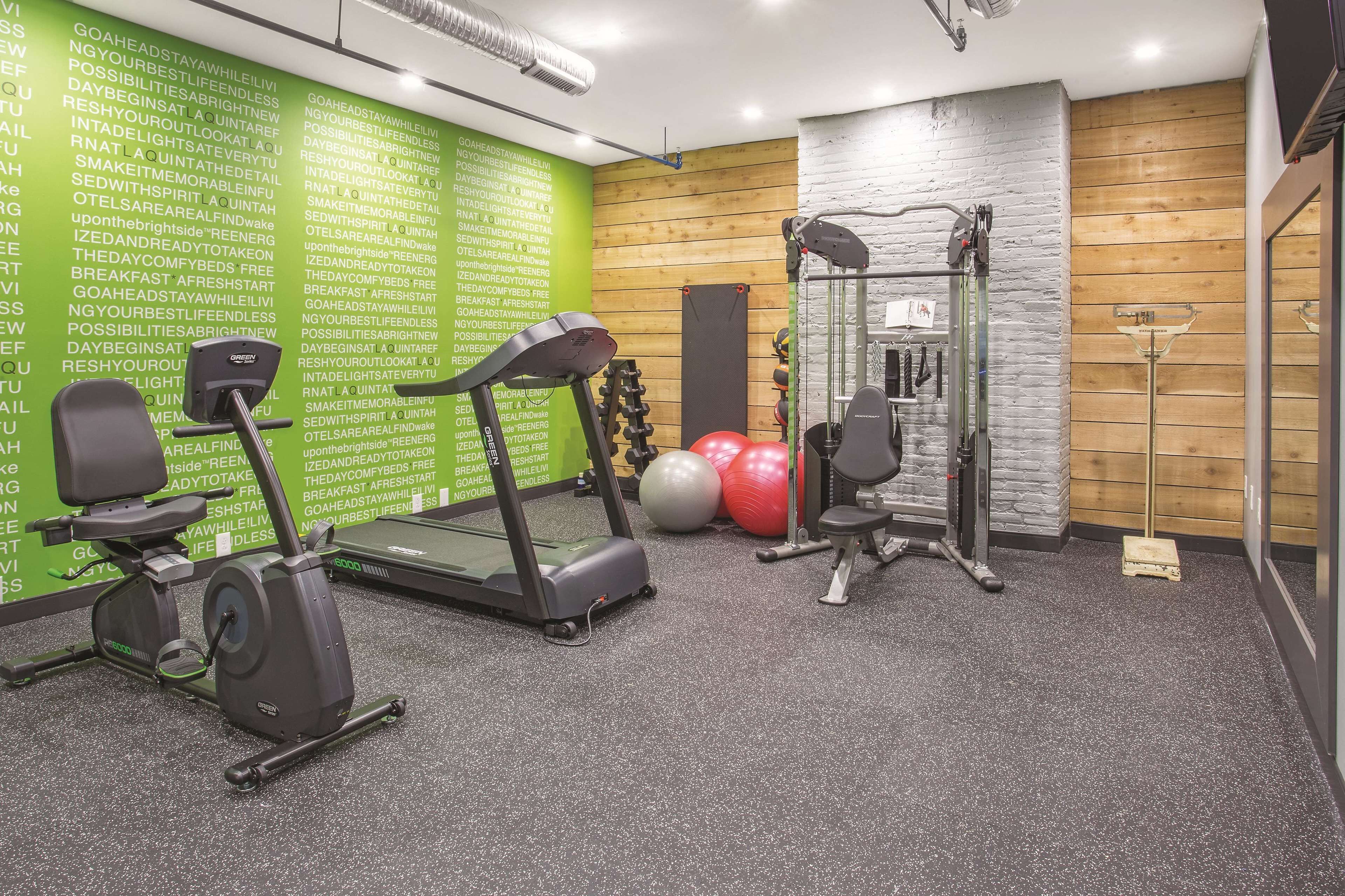 A gym with treadmills, an elliptical, a weight machine, and exercise balls.