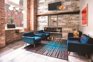 Un salón moderno con paredes de ladrillo, un ventanal grande y asientos azules.